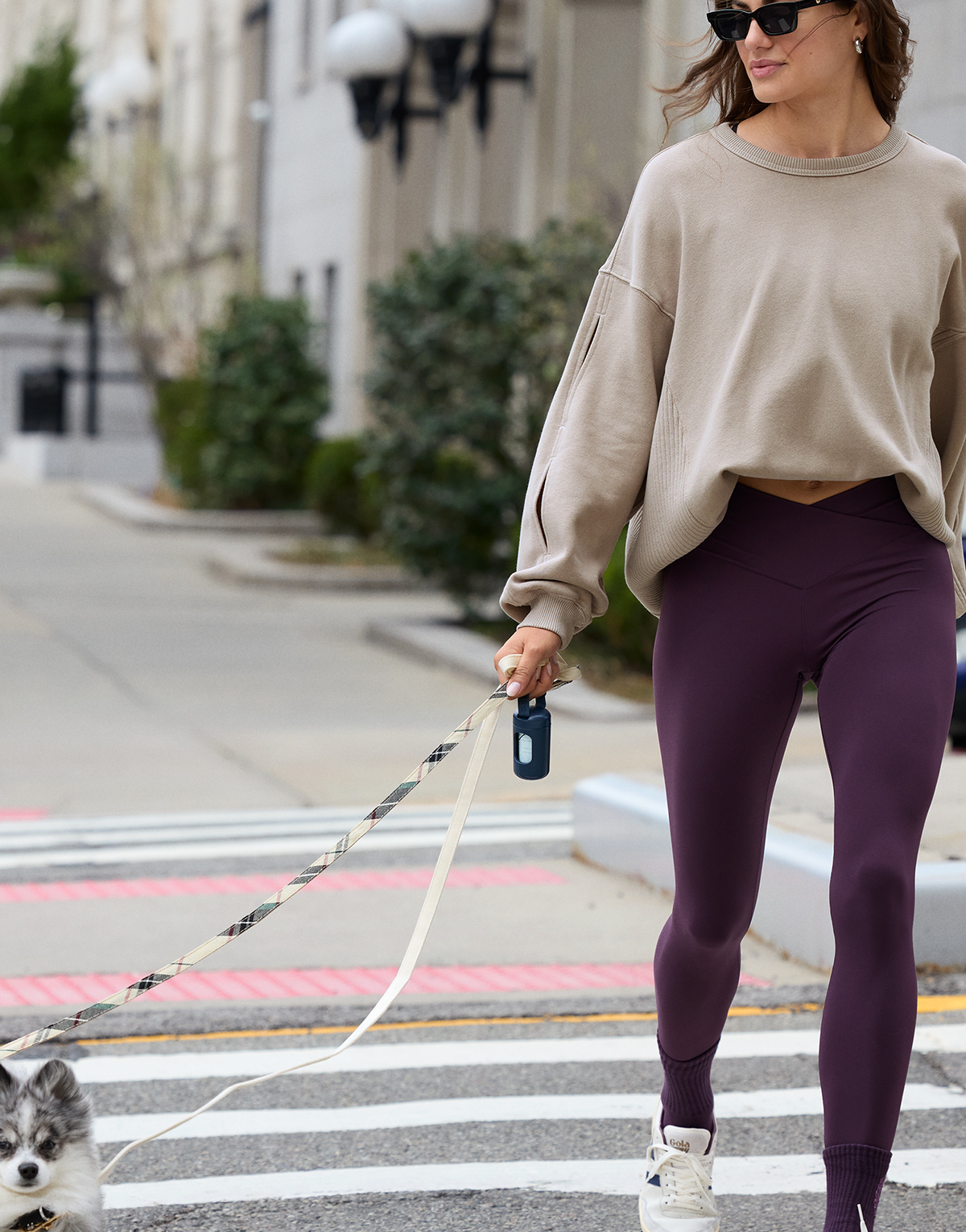 Woman walking her dog in a fall outfit.