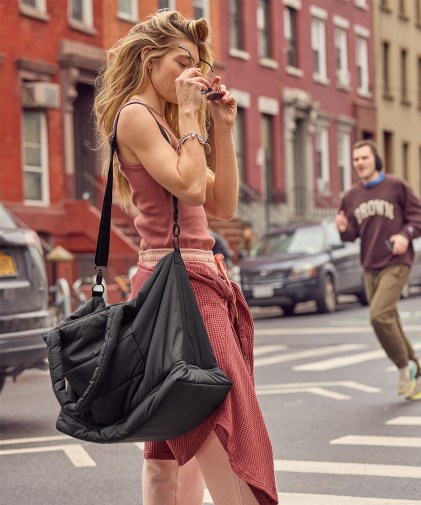 A woman wearing Aerie travel loungewear and carrying a tote.
