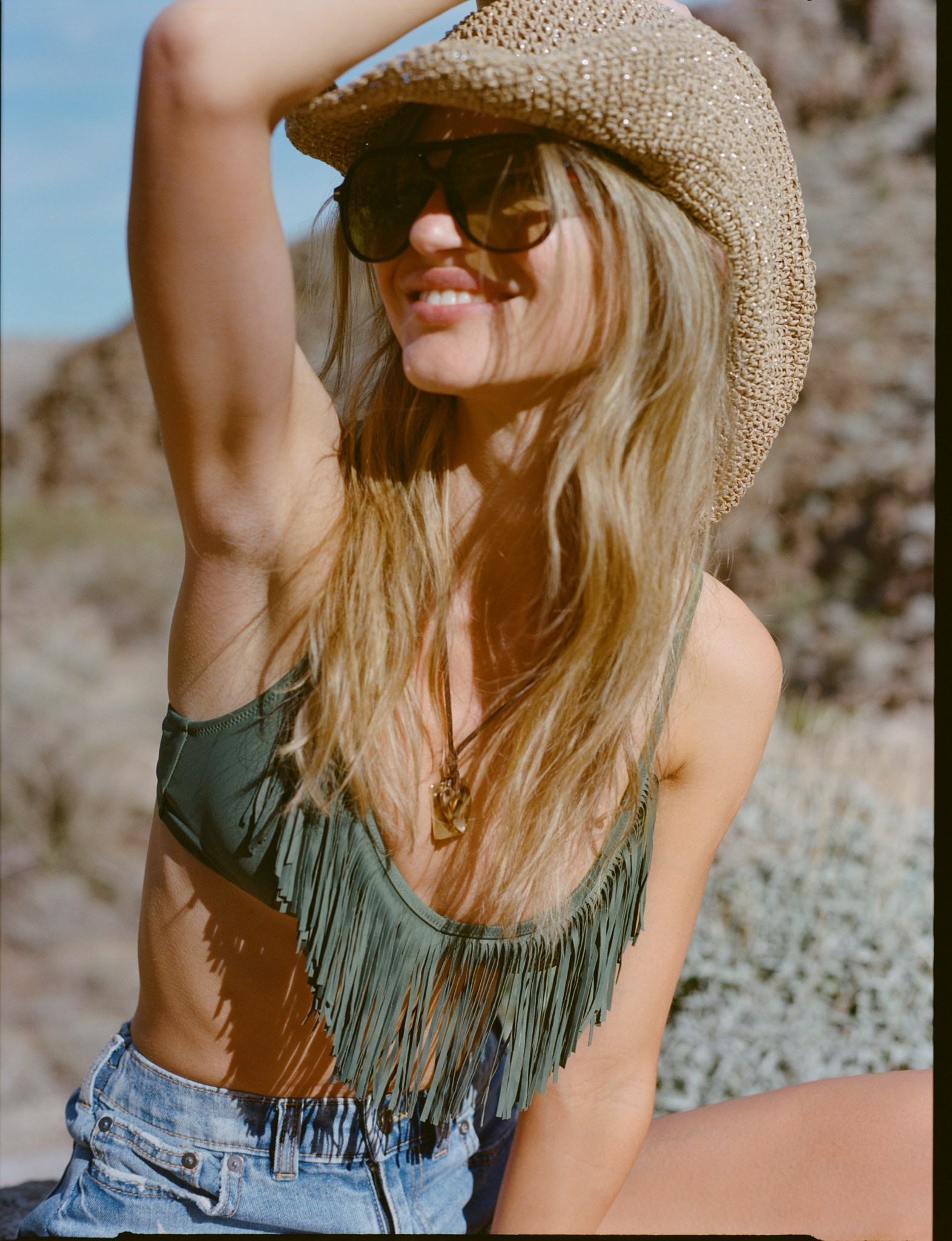 Woman wearing Aerie fringe top and denim shorts.